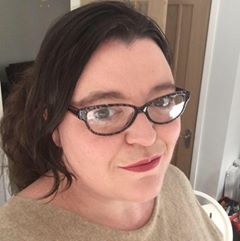 Head and shoulders photograph of Sarah Ford, with dark hair and glasses